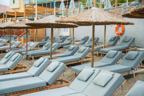 a row of blue lounge chairs and umbrellas on a beach at AKASHA Beach Hotel & Spa in Hersonissos