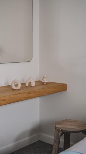 a shelf on a wall with a table and a mirror at Serene Shore Serifos in Alona