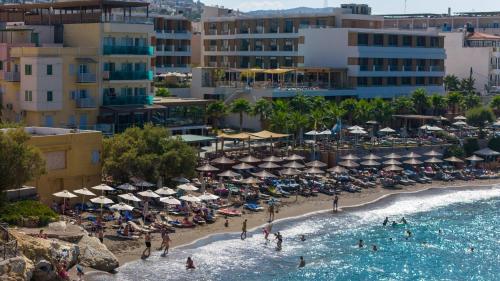 a beach with umbrellas and people in the water at AKASHA Beach Hotel & Spa in Hersonissos