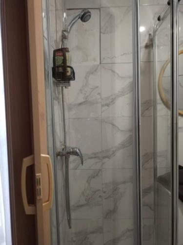 une douche avec une pomme de douche et une porte vitrée dans l'établissement Chez Gabin & Elsie, à Pertuis