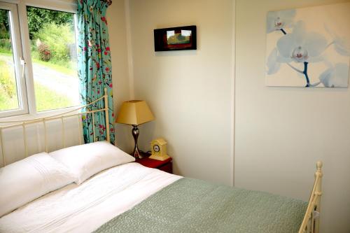 a bedroom with a bed and a window at Cabin Cynthia in Llwyngwril