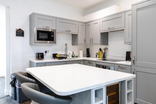 a kitchen with white cabinets and a white counter top at Beach Haven, Steps to Sand, Trails & Shops, Highly Rated 2-Bedroom House Minutes from Mumbles Beach with a Patio in Oystermouth