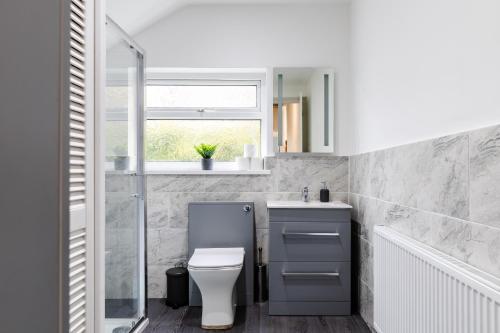 a bathroom with a toilet and a sink and a window at Beach Haven, Steps to Sand, Trails & Shops, Highly Rated 2-Bedroom House Minutes from Mumbles Beach with a Patio in Oystermouth