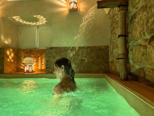 a woman in a swimming pool with a waterfall at Cuturissi Hospitality & Wellness in Ragusa