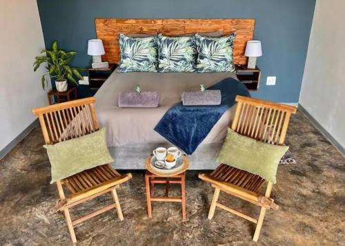 ein Schlafzimmer mit einem großen Bett mit zwei Stühlen in der Unterkunft Verdiend En-suite Unit at Ngweni Private Game Farm in Hluhluwe