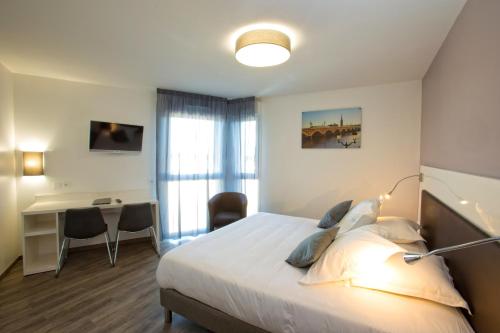 a hotel room with a bed and a desk and a bedroom at All Suites Appart Hôtel - Bordeaux - Pessac in Pessac