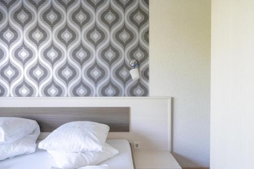 a bedroom with two pillows on a bed with a wallpaper at FarawayHomes Aparthotel Near Vienna Airport - Anytime Self Check-In in Bruck an der Leitha