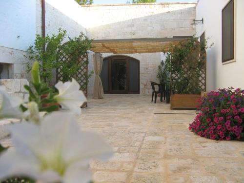 un patio con flores y suelo de piedra en B&B Masseria Spilafemine, en Turi