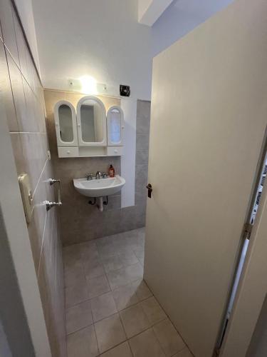 a bathroom with a sink and a mirror and a door at EL departamento con estilo in San Fernando del Valle de Catamarca