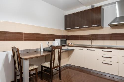 a kitchen with white cabinets and a table and chairs at FarawayHomes Aparthotel Near Vienna Airport - Anytime Self Check-In in Bruck an der Leitha