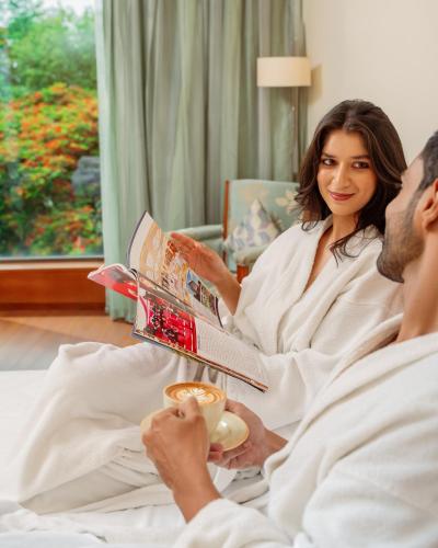 a man and woman sitting in bed reading a magazine at Hyatt Pune in Pune