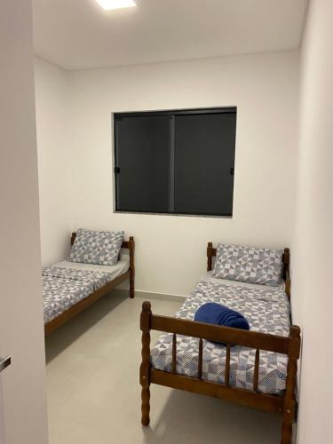 a room with two beds and a flat screen tv at Lindo Sobrado em Camboriú in Camboriú