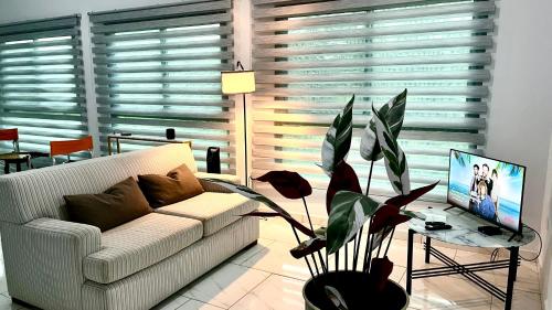 a living room with a white couch and a plant at Acogedor apartamento con hermosa vista al volcán - The Goat Spot - planta alta in Alto Boquete