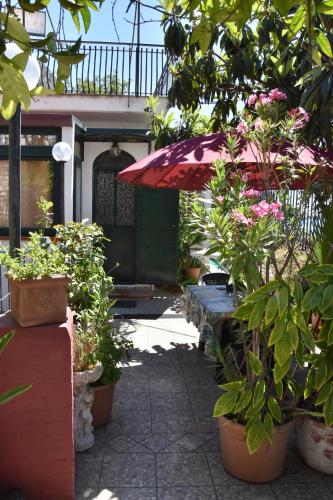 a patio with potted plants and a red umbrella at Holiday Home Gionny & Mary in Taormina