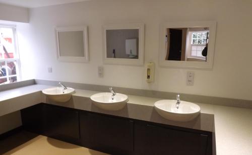 a bathroom with three sinks and two mirrors at Jersey Accommodation and Activity Centre in Gorey