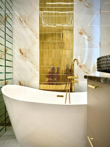a bathroom with a tub and a gold shower at Allure GALAXY Centrum Aparthotel in Szczecin