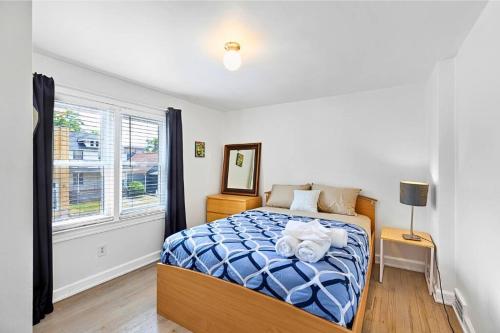 a bedroom with a bed with a blue comforter and a window at Luxury Downtown Retreat - Prime Spot - Sleeps 6 in Royal Oak