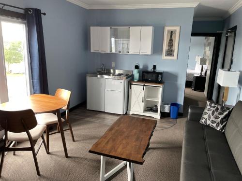 a living room with a table and a kitchen at Acadian Hotel in Stephenville