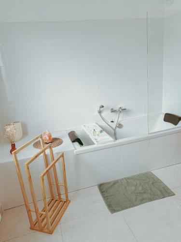 La salle de bains blanche est pourvue d'une chaise et d'une baignoire. dans l'établissement Maison Dune - mer & douceur de vivre à Plouha, à Plouha