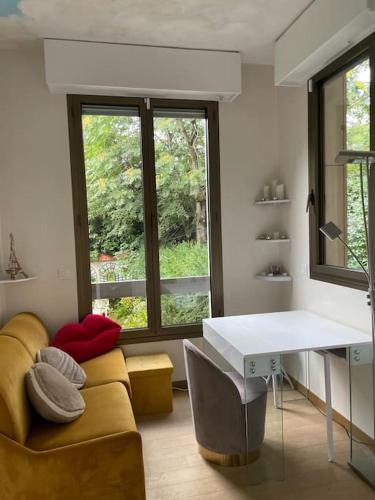 - un salon avec un canapé, un bureau et une fenêtre dans l'établissement Studio cadre bucolique Neuilly Paris, à Neuilly-sur-Seine