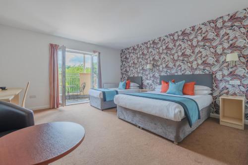 a hotel room with two beds and a table at Wookey Hole Hotel in Wells
