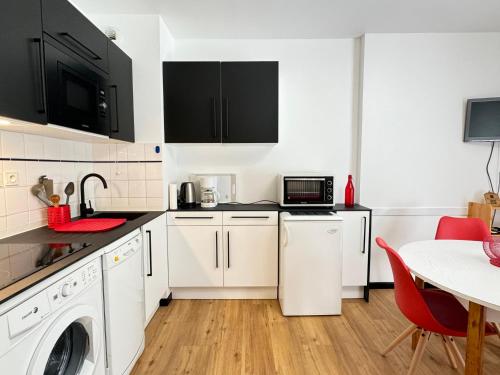 une cuisine avec des placards blancs et une table avec des chaises rouges dans l'établissement T3 duplex 6 couchages parking et balcon sud, à Cauterets
