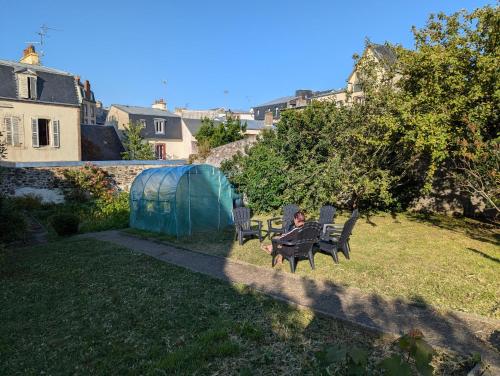 une personne assise sur une table dans une cour dans l'établissement Le Jardin en centre ville - ANCV accepté, à Granville