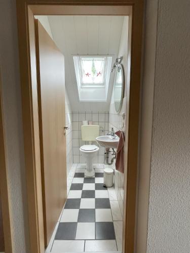 a bathroom with a sink and a toilet with a window at Hennis Huuske in Krummhörn