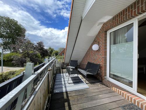 a deck with a chair and a window on a house at Hennis Huuske in Krummhörn