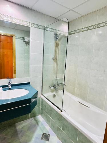 ein Badezimmer mit Badewanne, Waschbecken und Dusche in der Unterkunft Bliss Square Hotel in Dubai