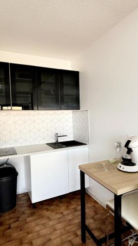 a white kitchen with a sink and a table at Loft en plein centre, Vue port in Cap d'Agde