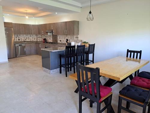 a kitchen and dining room with a wooden table and chairs at Villa avec piscine, Hacienda Beach Sidi Rahal in Sidi Rahal