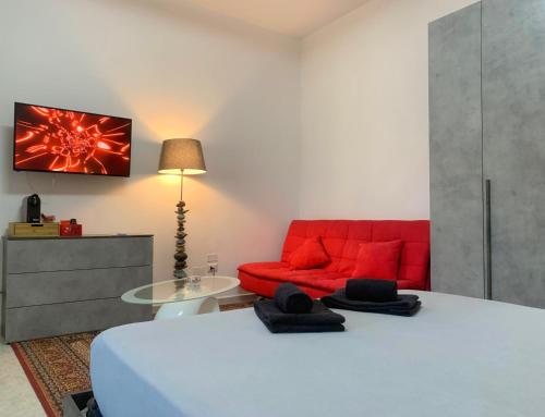 ein Schlafzimmer mit einem Bett und einer roten Couch in der Unterkunft Mini Red Hub - Design Apartment in SantʼAgapito