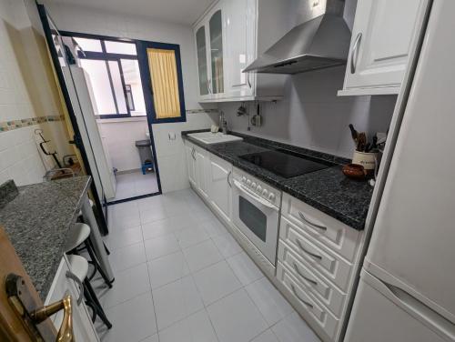 a kitchen with white cabinets and a stove top oven at Apartamento El Eden in Playa de Gandia