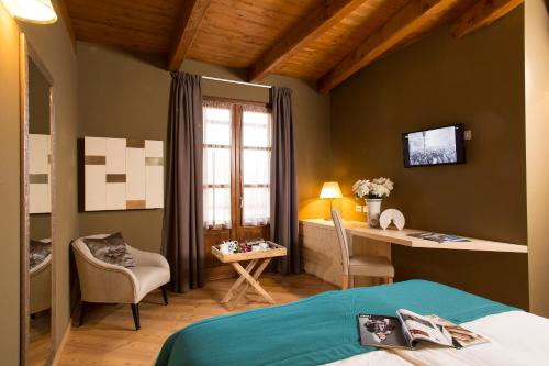 a bedroom with a bed and a desk and a window at La Burla in Borgosesia