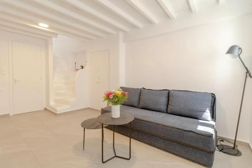 a living room with a couch and a table with flowers at Skepi Town Houses in Mikonos
