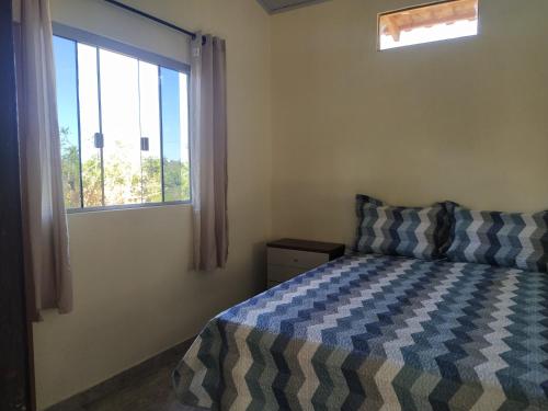 a bedroom with a bed and a window at Chalé do Ypê in Pirenópolis