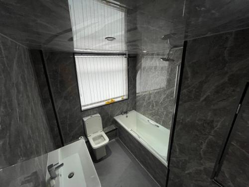 a bathroom with a toilet and a tub and a sink at Pc home Room A in Hyde