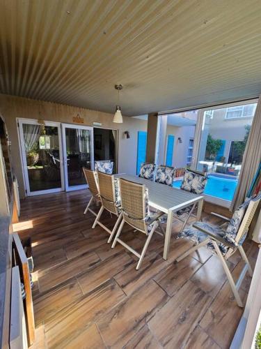 a screened in porch with a table and chairs at Vibe Beach House in Herolds Bay