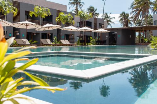 - une piscine dans un complexe avec des parasols dans l'établissement Flat Villas Manatee Rota Ecológica dos Milagres, à Porto de Pedras