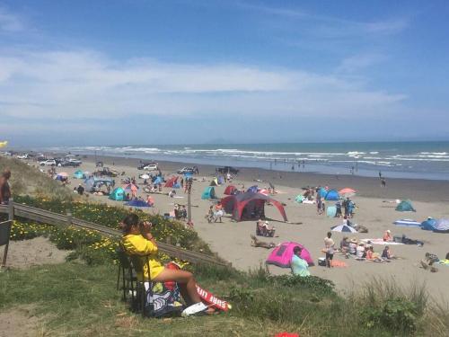 a group of people on the beach at the beach at Relaxed Beach Retreat, mod family friendly bach in Foxton Beach