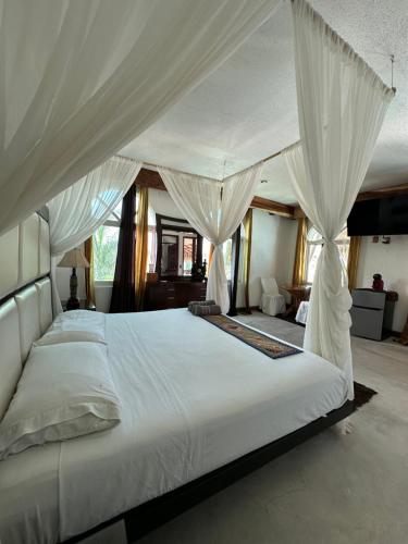a bedroom with a large white bed with curtains at Hotel Boutique Punta Jamaica in Acapulco
