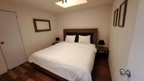 una camera da letto con un letto con lenzuola bianche e due lampade di 3 RECS: HERMOSO,AMPLIO E INMEDIATO A PASEO REFORMA a Città del Messico