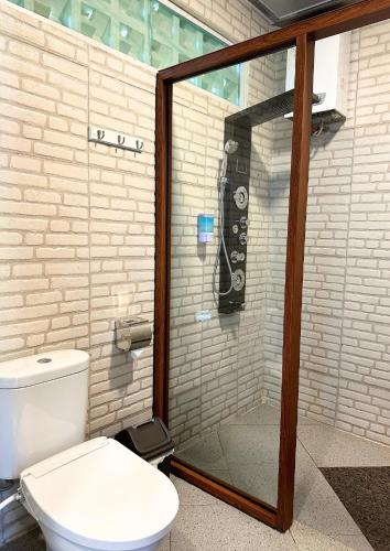 a bathroom with a glass shower with a toilet at De Pointé Resort & Resto in Campaka