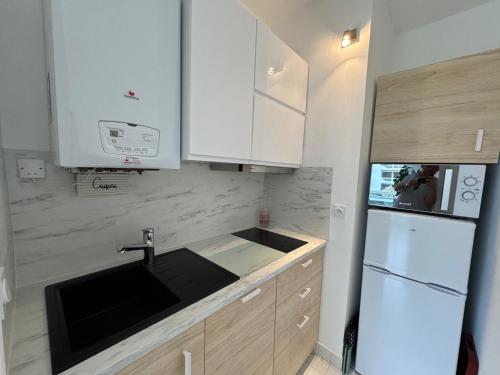 une cuisine avec des armoires blanches, un évier et un réfrigérateur dans l'établissement Appartement à Arcachon : Plage à 50m, Terrasse, Parking, WIFI, 4 Pers - FR-1-474-266, à Arcachon