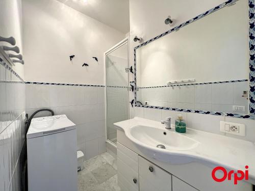 une salle de bain blanche avec un lavabo et un miroir dans l'établissement Appartement tranquille avec piscine et WiFi à Menton - FR-1-647-37, à Menton