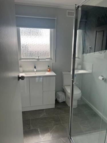 a bathroom with a sink and a toilet and a window at Cowes Cosy Cottage in Phillip Island