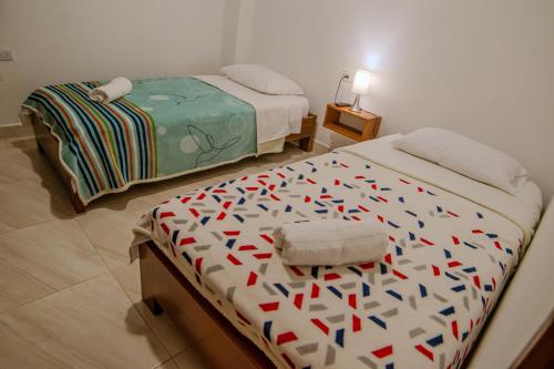 a bedroom with two beds with colorful comforters on them at Apartahotel La Gruta in Jericó
