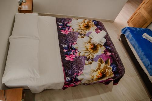 a bed with a blanket with flowers on it at Apartahotel La Gruta in Jericó