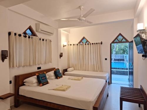 a bedroom with two beds and a window at Villa Goodwill Paradise in Hikkaduwa